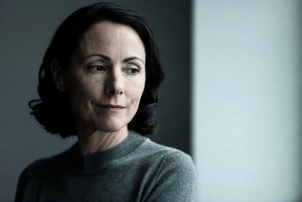 A woman in her forties looking away from camera in soft, cool daylight.